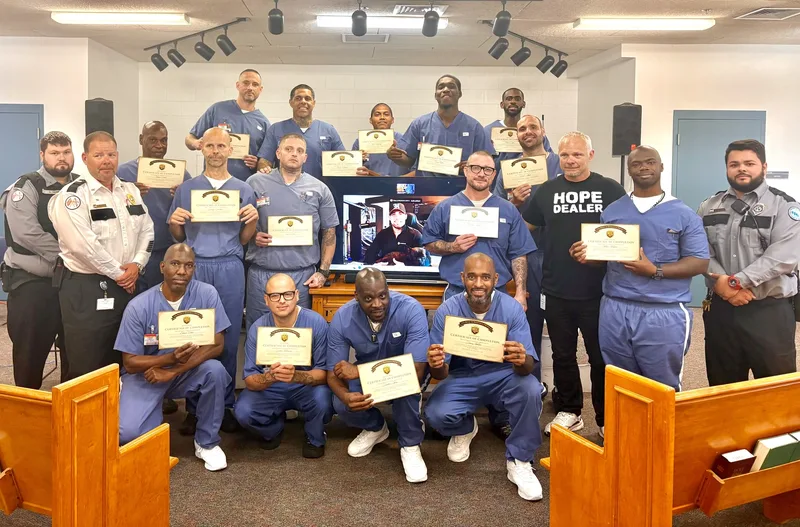 RTD program graduates holding certificates of completion inside a prison chapel