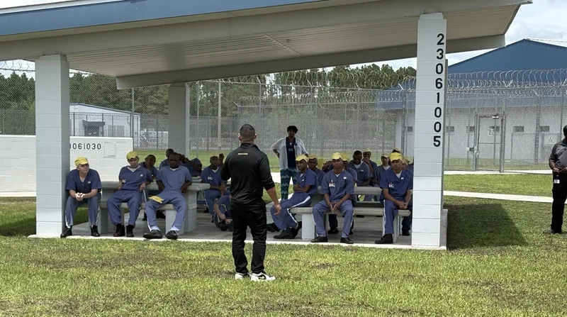 Frank Ortega teaching a group of young men seated under a pavilion in a prison yard
